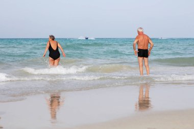 Tunus, 06.13.2019: Yaşlılar denize giriyor. Kumsaldaki yaşlı adamlar. Mutlu emeklilik. Yaşlıların geri kalanı sahilde. Seyahat eden yaşlılar.