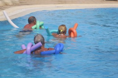 Tunus 06.20.2019. Birkaç kişi havuzda aerobik yapıyor. Tatil yapan turistler. Su aktiviteleri. Havuzdaki mutlu bir grup yüzen eriştelerle su sporu yapıyor..