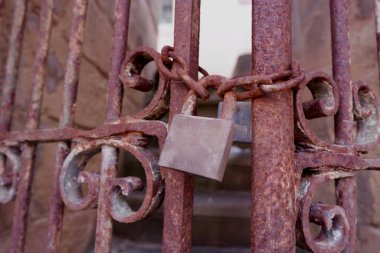 Kilitli paslı bir kapı ve zincir terk edilmiş bir evin merdivenlerini kapatıyor.