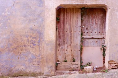 Pastel renkli duvara karşı eski ahşap bir kapı terk edilmiş bir evin girişini kapatır. Sos del Rey Catolico, Aragon, İspanya 