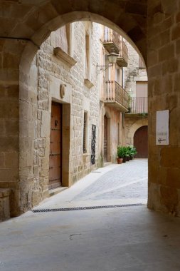 Calaceite Köyü, Teruel, Aragon / İspanya - 31 Mart 2019: Bir turist köyünün boş caddesi, kemerin altındaki antik avlunun girişi.
