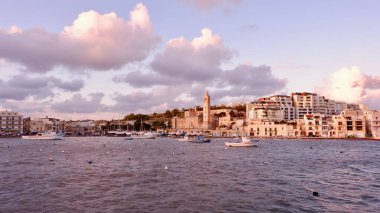Malta 'nın yaşlı Akdeniz şehri Marsaskala' nın panoraması. Sabah vakti tipik balıkçı tekneleri olan renkli deniz manzarası. Sıcak kırmızı ışık.