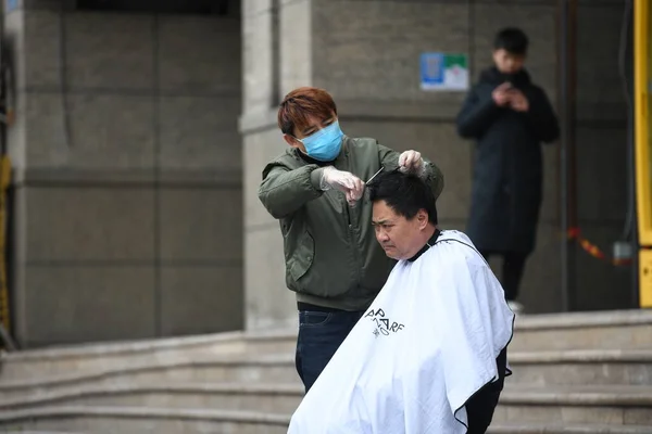 据法新社3月4日报道 一名理发师日前在重庆的余贝区为街上的一个人理发 — 图库照片