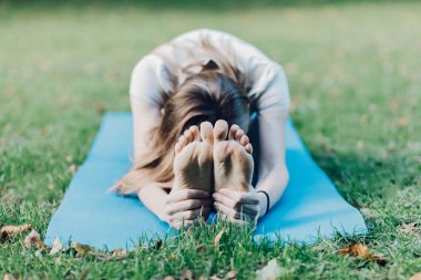 Güzel genç kız yaz parkında esneme hareketleri yapıyor.