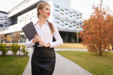Young office worker with documents in hands on the background of a office building