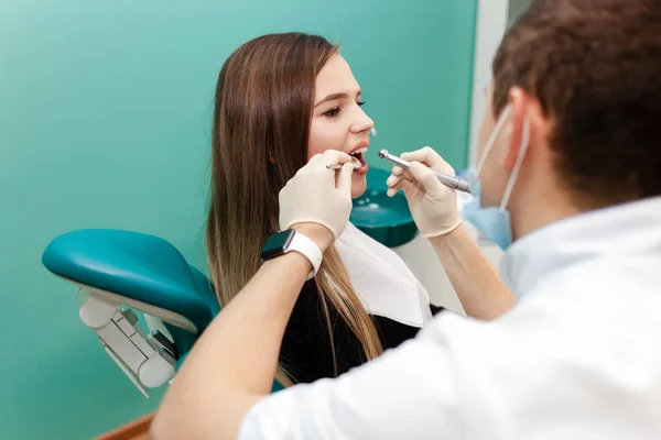 Dentist with a drill and a mirror is treating a patient teeth