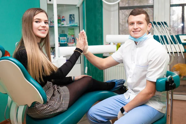 Satisfied patient gives five to the dentist after treatment