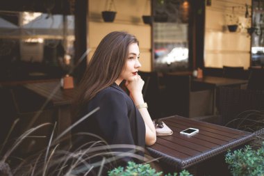 Kafe masasındaki güzel yalnız bayan düşünceli görünüyor.