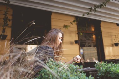 Yalnız bir kadın restoranda otururken saate bakar.