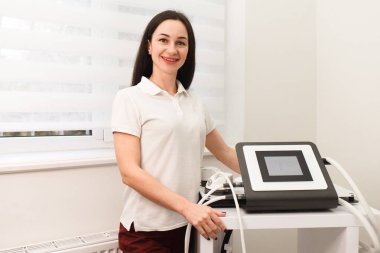 Doktor kozmetolog elinde vakum antiselülit masajı için bir cihaz tutuyor.