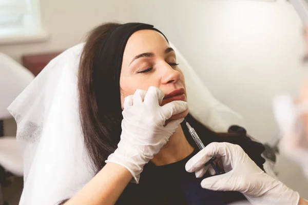 Woman fights facial wrinkles. Doctor cosmetologist gives a chin injection for patient