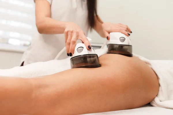 Cosmetologist makes buttock vacuum massage procedure for client. Doctor uses endomassage device
