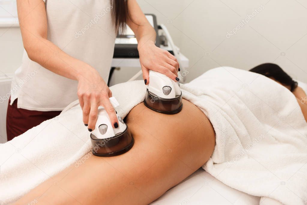  Cosmetologist makes buttock vacuum massage procedure for client. Doctor uses endomassage device