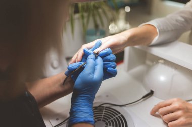 Manikürcü, müşterilerin tırnağını uçla keser.