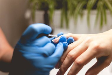 Manikürcü müşterinin tırnaklarını cilalayıp Fransız usulü yapıyor. Manikür süreci kapat