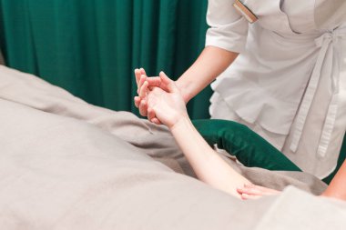 Doktor kozmetik uzmanı hastasının ellerine masaj yapıyor. Güzellik salonu müşterisi el masajından hoşlanır.