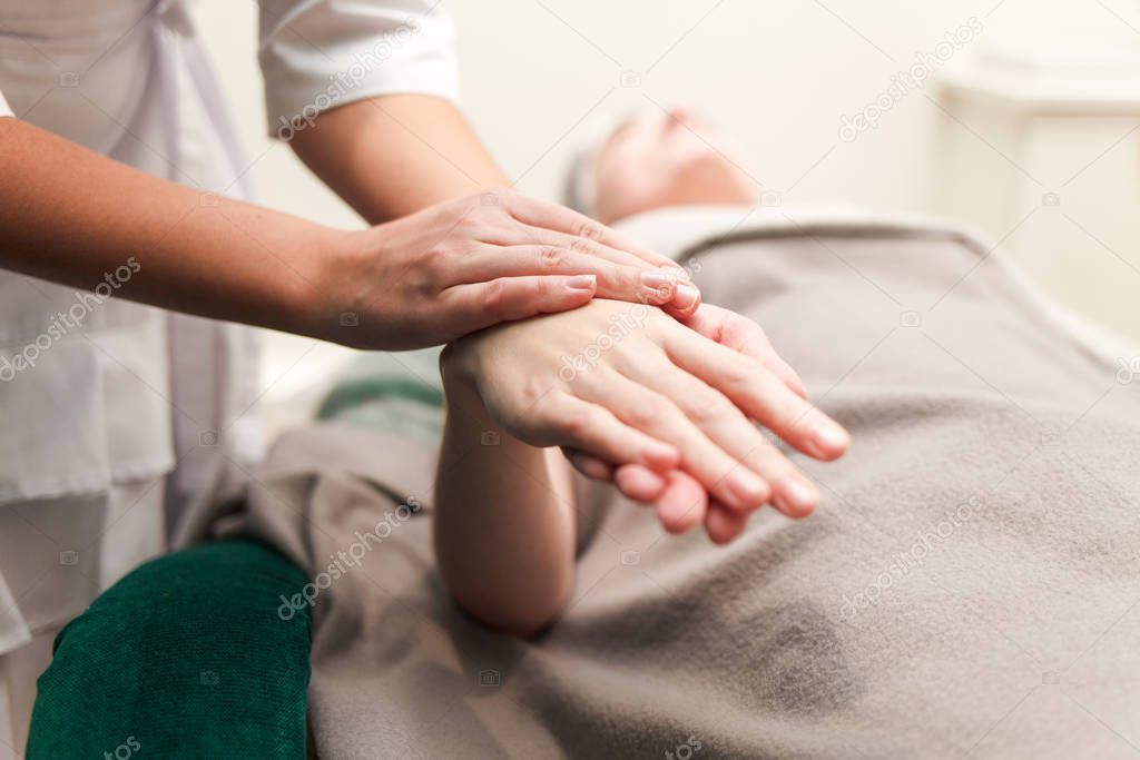 Doctor cosmetologist massages the hands of his patient. Client of a beauty salon enjoys a hand massage