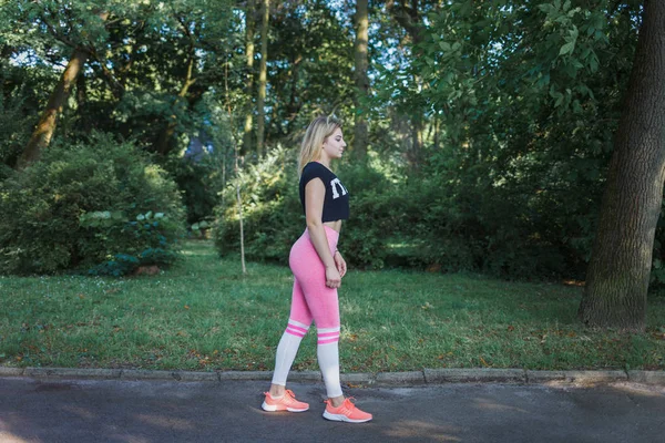 Vista lateral da jovem em forma no sportswear se preparando para o treino. Mulher saudável no parque — Fotografia de Stock