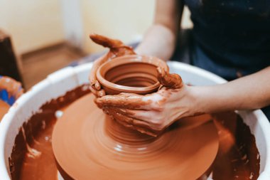 Kadın çömlekçilikle meşgul. Potter çömlekçinin çarkının arkasında seramik yemekler yapmak için kil oluşturur.
