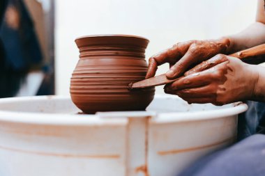 Kız çanak çömlek tekerinin arkasında çalışır ve mükemmel formlarda sürahi oluşturur.