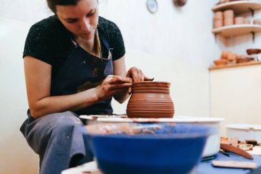 Kadın çömlekçilikle meşgul. Potter çömlekçinin çarkının arkasında seramik yemekler yapmak için kil oluşturur.