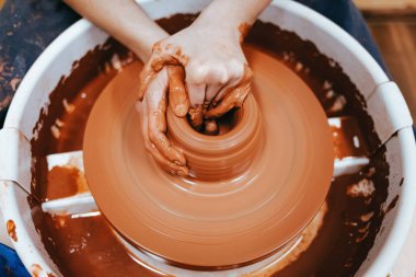 Potter kilden bir sürahi oluşturur. Seramik ürünler üretme süreci. Kadın çömlek çarkında çalışıyor.