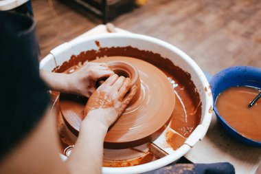 Potter kilden bir sürahi oluşturur. Seramik ürünler üretme süreci. Kadın çömlek çarkında çalışıyor.