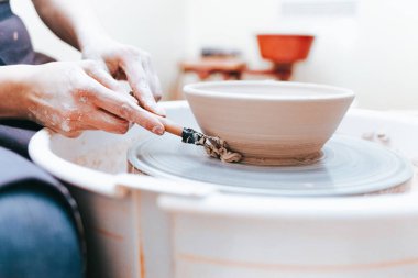 Beyaz kil seramik plaka oluşturma ve oluşturma süreci. Profesyonel çömlekçi kil levhaları modellemekle meşgul. Potter bir atölyede çalışıyor.