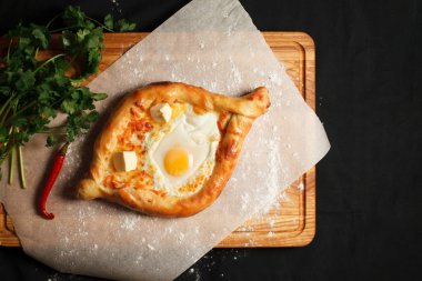 Geleneksel Gürcü yemeği khachapuri ajarian siyah arka planda. Taze pişmiş Khachapuri. Peynirli ve çiğ yumurtalı Ulusal Gürcü hamur işleri