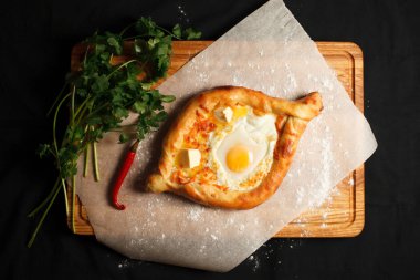 Geleneksel Gürcü yemeği khachapuri ajarian siyah arka planda. Taze pişmiş Khachapuri. Peynirli ve çiğ yumurtalı Ulusal Gürcü hamur işleri