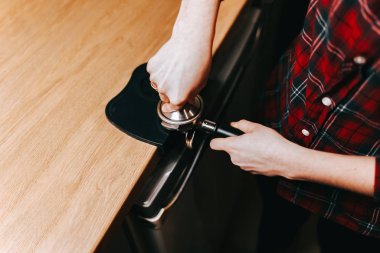 Barista kahveyi kurcalayarak ütülüyor. Alet kurcalayıcı. Kahve makinesi paslanmaz çelikten yapılır.
