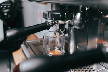 Kokulu espresso kahve makinesinden fincana akar. Profesyonel kahve ekipmanlarıyla aromatik kahve yapmak.
