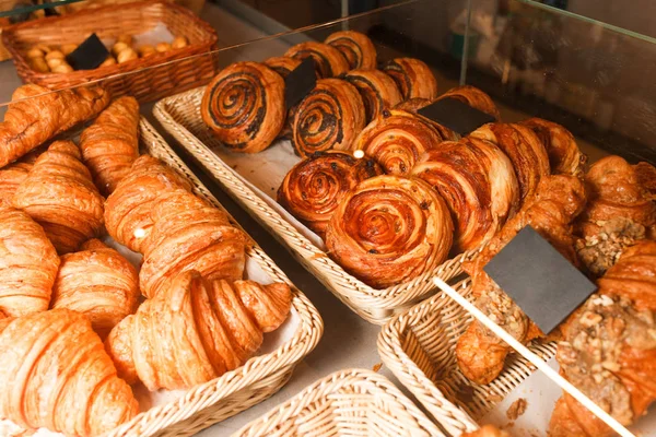 Delicious freshly baked pastries in a pastry shop. Many buns and croissants on a shelf of a baking shop