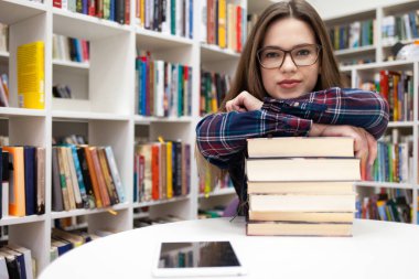 Güzel bir öğrenci başını bir yığın kitabın üzerine yasladı. Kütüphane konseptinde genç bir kadın