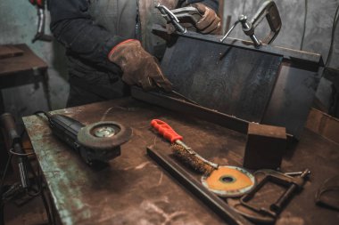 Adam demir ürünleri c-klemplere sıkıştırıyor. Adam klemplerle çalışıyor. Çelik atölyesi konsepti.