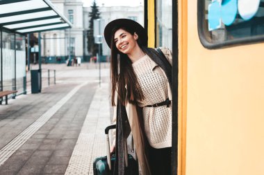 Beautiful girl tourist in coat and hat peek out of a tram door