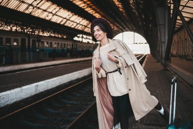 Neşeli genç bayan gezgin tren istasyonunda trenini bekliyor.