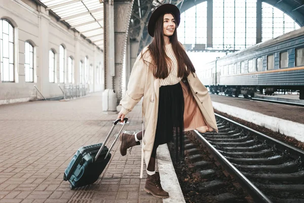 Neşeli genç bayan gezgin tren istasyonunda trenini bekliyor.