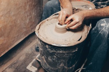Adam çömlek çarkında beyaz kilden bir ürün oluşturuyor.