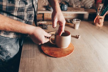 Potter seramik bardak üzerinde çalışıyor.