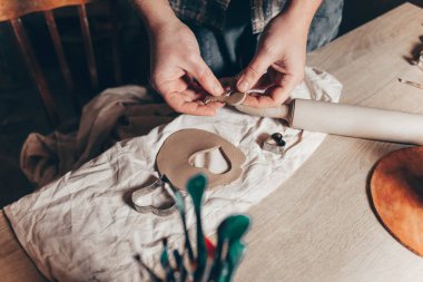 Potter elinde kilden bir kalp şeklinde bir süs tutuyor.