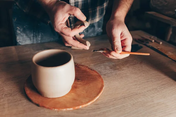 Potter glues ears to a cup. Process of creating a ceramic cup