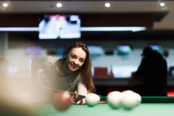 Gambling woman plays snooker in a billiards club