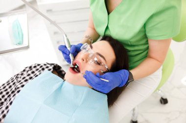 Genç ve güzel bir kadın dişçi dolabında dişlerini tedavi ediyor. Diş tedavisi süreci