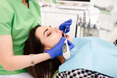 Genç ve güzel bir kadın dişçi dolabında dişlerini tedavi ediyor. Diş tedavisi süreci