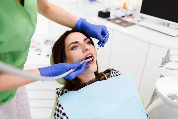 Young beautiful woman treats teeth at the dentist cabinet