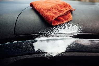 Arabanın kokpitinde mikrofiber bez ve köpük. Otomatik temizleme kavramı