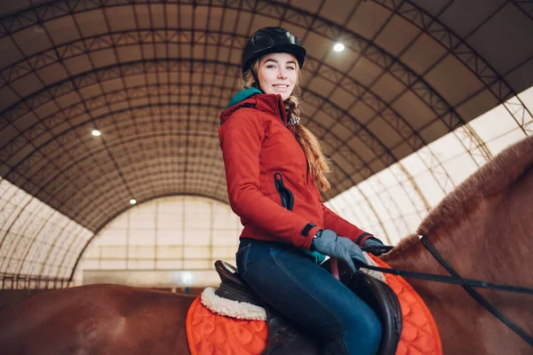 Positive woman riding a horse in the arena