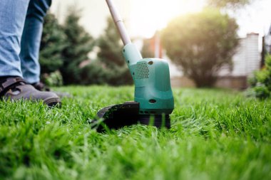 Adam çimleri elektrikli budayıcıyla kesiyor..