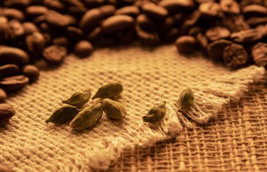 Çuval bezeli kakule fasulyelerini kahve çekirdeklerinin arka planında izole ettim.